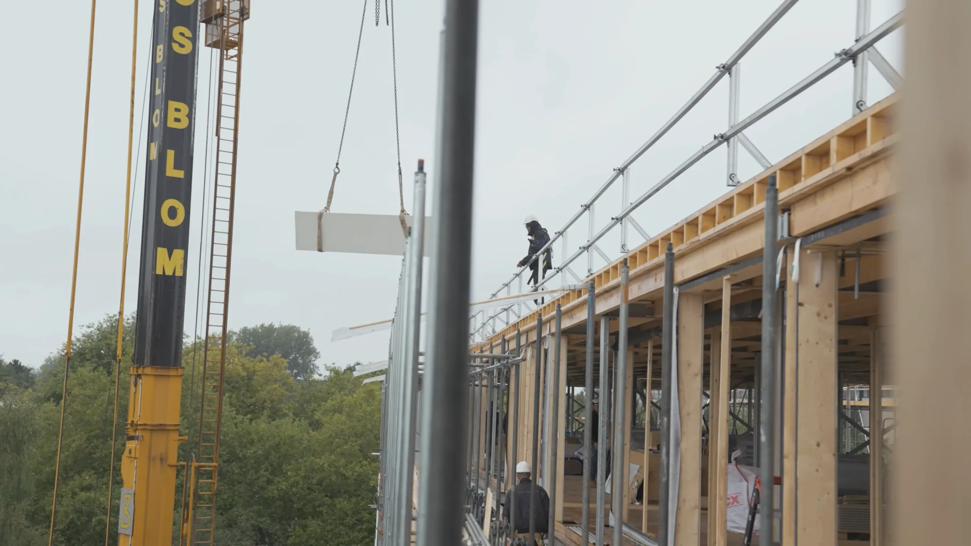 Optopping in aanbouw: een kraan hijst een dakelement naar de nieuwe houten verdieping