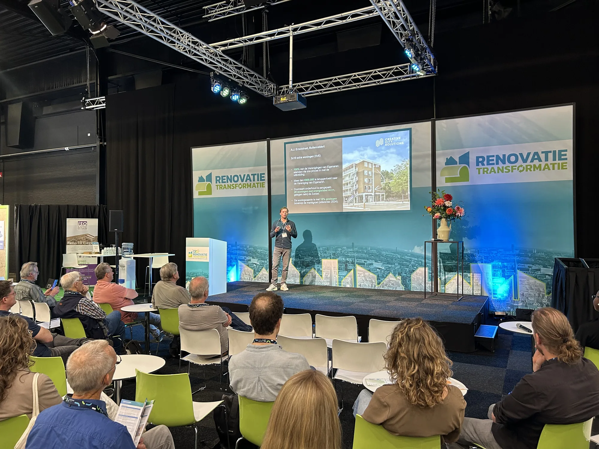 CCS op het podium van de Renovatie & Transformatiebeurs, met een slide over het optopproject aan de A.J. Ernststraat.