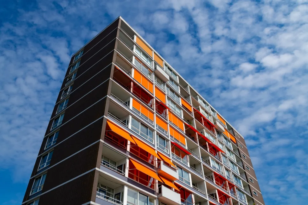 Flatgebouw met gekleurde zonneschermen op de balkons.