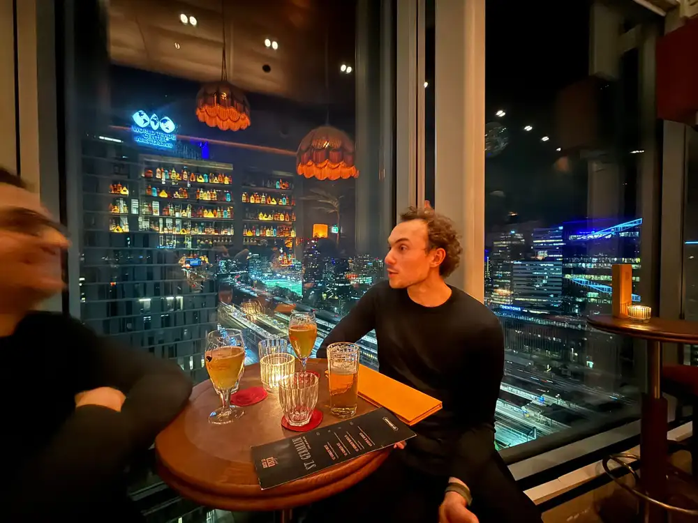 Aan tafel bij het raam in de avond, met de lichten van de stad erachter