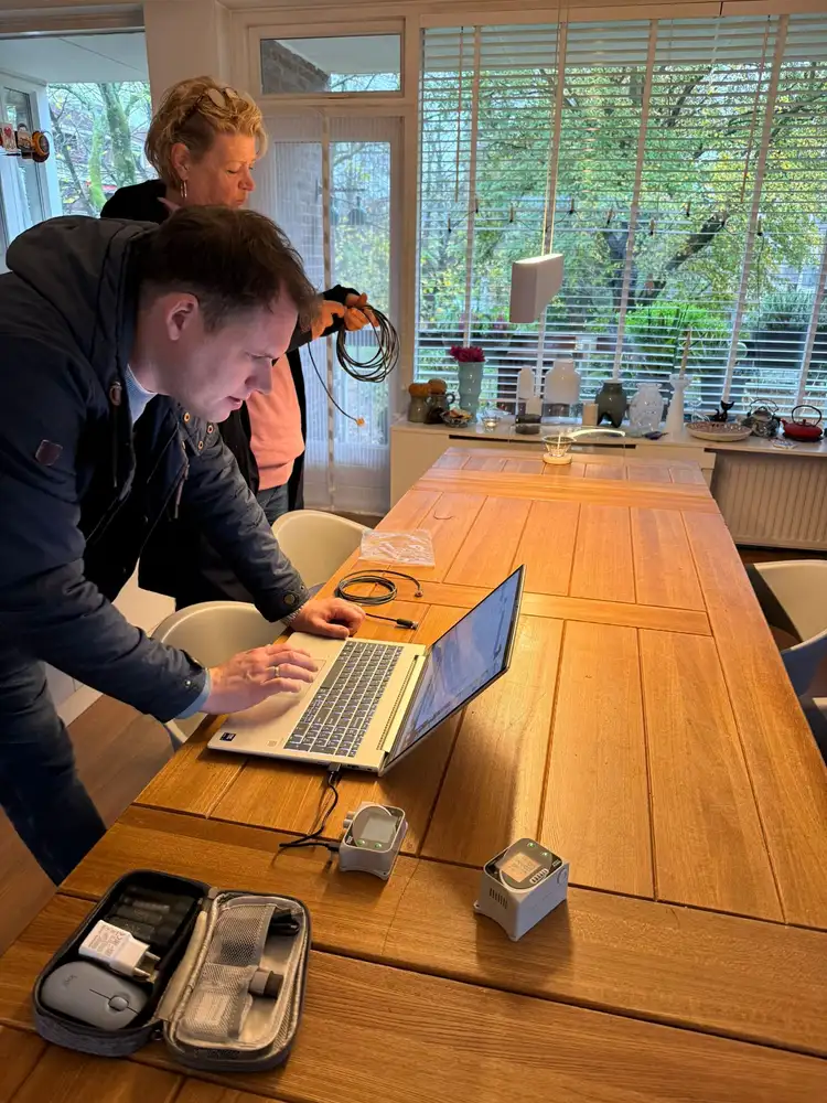 Werken aan de lange houten tafel op kantoor, met laptops bij het raam