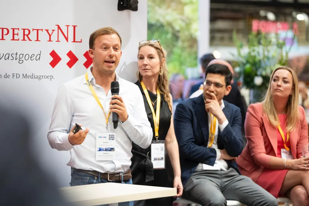 Een spreker met microfoon tijdens een paneelgesprek op een evenement